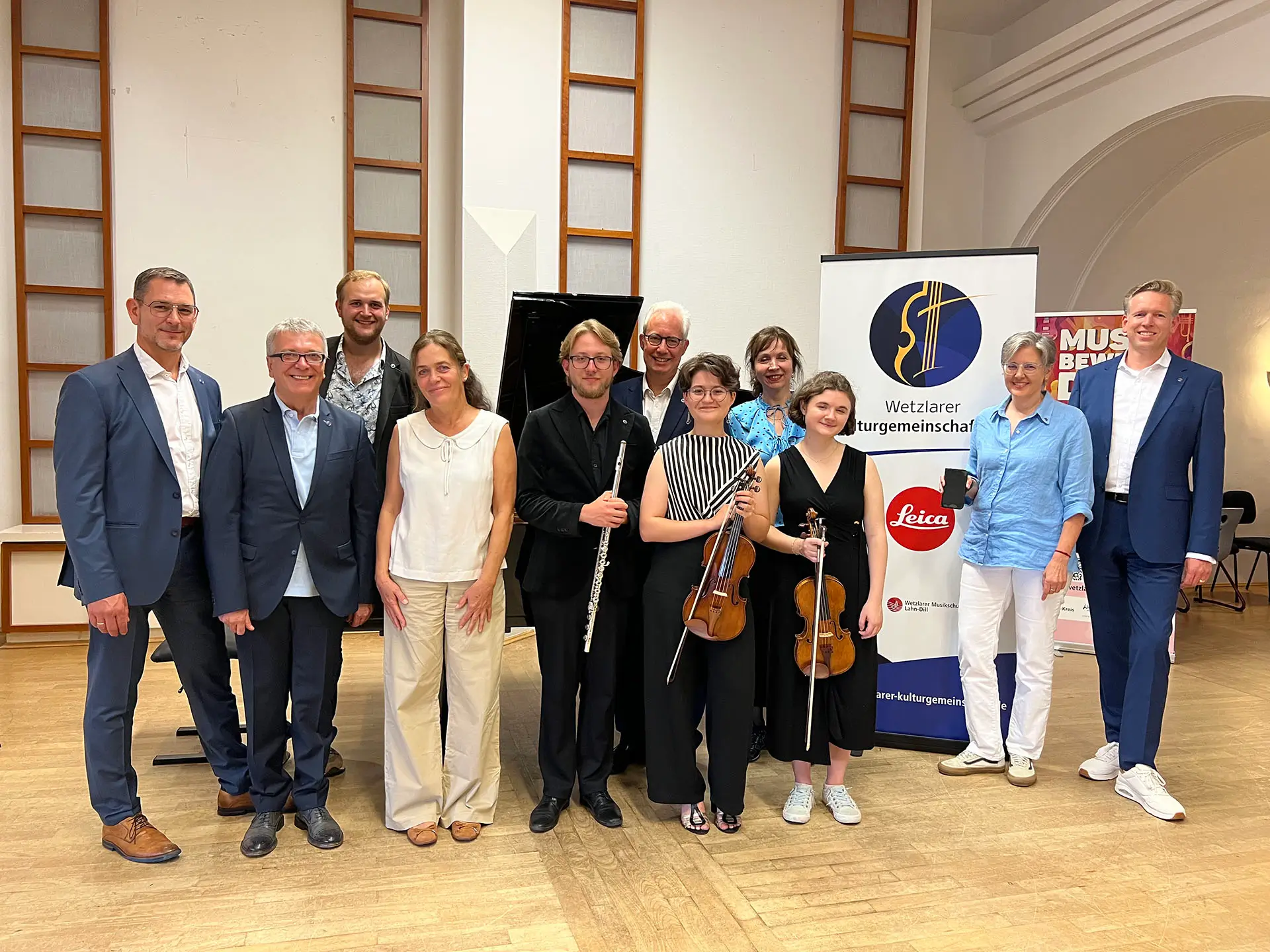 Elsie Kühn-Leitz Stipendium 2026/27; Gruppenbild vor Plakat der Wetzlarer Kulturgemeinschaft